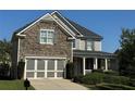 Two-story home with stone and siding accents, three-car garage, and landscaped yard at 4335 Silent Path, Cumming, GA 30028