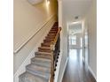Carpeted staircase with wooden railing leads to the upper level of the home at 5831 Taka Ln, Lithonia, GA 30038