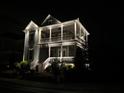 Two-story home featuring a double porch and illuminated by landscape lighting in a nighttime setting at 7460 Cordery Rd, Cumming, GA 30040