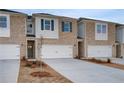 Townhome exteriors boasting brick, white garage doors, and newly installed landscaping at 305 Heavenly Hollow Pl, Mcdonough, GA 30253