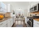 Bright kitchen featuring white cabinets, granite countertops, stainless steel appliances, and a dining nook with backyard view at 642 Jenmarie Sw Dr, Mableton, GA 30126