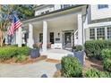 Inviting front porch features classic columns, a welcoming seating area, and manicured landscaping at 5760 Windjammer Pt, Cumming, GA 30041