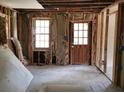 Interior view of a room with exposed framing, a wooden door, and two windows at 5325 Victory Blvd, Morrow, GA 30260