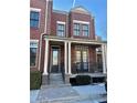 Charming brick townhouse featuring black-framed windows and a welcoming front porch with columns at 4666 Magnolia Commons, Dunwoody, GA 30338