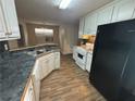 The kitchen features black appliances, white cabinets and vinyl floors at 40 Brandon Dr, Covington, GA 30016