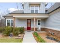 A welcoming porch with a red door, rocking chair, and charming landscaping creates a warm entry at 260 Harmony Woods Dr, Dallas, GA 30157