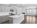 Modern kitchen with stainless steel appliances, island, and open to the living room with fireplace at 404 Village Ln, Fairburn, GA 30213