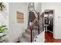 Carpeted staircase featuring decorative iron spindles and access to a half bathroom offers functional elegance at 5619 Cobblestone Creek Ave, Mableton, GA 30126