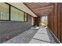 Covered walkway showcasing the home's modern design with wooden slats, gray brick, and a stone pathway to the entrance at 4351 Peachtree Dunwoody Ne Rd, Atlanta, GA 30342