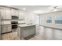 An open concept kitchen and living room space with stainless steel appliances and grey cabinetry at 5063 Lower Elm St, Atlanta, GA 30349