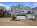 Stylish townhome featuring a two-car garage and brick driveway, set against a backdrop of trees and blue sky at 100 Duval Dr, Alpharetta, GA 30009