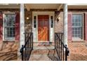 Inviting front porch with brick columns, dark wood door, decorative shutters, and well maintained landscaping at 2658 Stonehenge Ct, Dunwoody, GA 30360