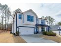 Exterior shot showcasing two story home with blue trim, a two-car garage, and a modern design at 3410 Summerpoint Xing, Cumming, GA 30028