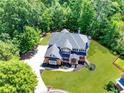 Aerial view of home showcasing lush landscaping, driveway, and serene, wooded surroundings at 6690 Bridge Brook Ovlk, Cumming, GA 30028