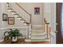 Foyer staircase with white banisters and wood handrail adds classic charm at 12015 Wildwood Springs Dr, Roswell, GA 30075