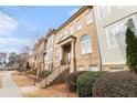 An exterior angle view of a brick townhome showcasing landscaped bushes and an ascending front staircase at 2447 Gatebury Cir, Chamblee, GA 30341
