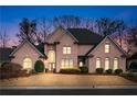 Charming brick home featuring well-maintained landscaping and a classic architectural style at dusk at 9135 Etching Overlook, Johns Creek, GA 30097