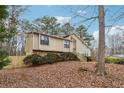 Exterior view of the home showing the sloped front yard and mature trees at 6664 Windwood Cir, Douglasville, GA 30135