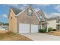 Brick home with a two-car garage and a well-manicured lawn on a bright sunny day at 610 Maltese Dr, Atlanta, GA 30349