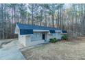 Ranch-style home features a brick facade, dark roof and door, trimmed bushes, and a lush, wooded landscape at 645 Plainville Sw Dr, Atlanta, GA 30331