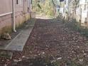 Side yard view showing the side of a house and narrow, leaf-covered outdoor space at 750 Alta Pl, Atlanta, GA 30318