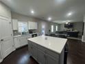 Open-concept kitchen with a large island, white cabinets, and a view into the living room at 557 Clinton Dr, Temple, GA 30179