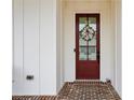 A charming front door is adorned with a floral wreath, set against a white exterior with brick flooring at 193 Idylwilde Way, Canton, GA 30115