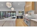 Modern kitchen featuring a Wolf range, waterfall island, pendant lighting, and sliding doors to the patio at 244 Brooke Dr, Alpharetta, GA 30009