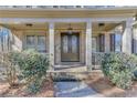 Inviting front porch featuring brick columns, double doors with iron detailing, and manicured landscaping at 6225 Leeward Tide Ct, Cumming, GA 30041