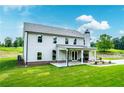 The rear exterior of this two-story home has a covered patio with a stone fireplace and a vast lawn at 878 Forrester Cemetery Rd, Covington, GA 30014