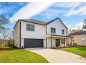 Charming two-story home with black trimmed windows, a well-manicured lawn, an inviting porch, and black garage door at 221 Cobb St, Palmetto, GA 30268