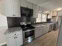 Renovated kitchen featuring gray cabinets, black backsplash, and stainless steel appliances at 536 Joann Ave, Austell, GA 30168