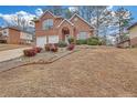 View of a two-story home with brick facade and arched entryway, surrounded by landscaping and a sloped front yard at 560 Woodstone Rd, Lithonia, GA 30058