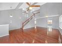 Bright living room with vaulted ceiling, hardwood floors, fan, and a staircase leading to an open landing area at 560 Woodstone Rd, Lithonia, GA 30058