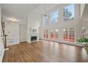 Open-concept living room with fireplace, hardwood floors, large windows, and access to the outdoor deck at 10440 Cranchester Way, Alpharetta, GA 30022