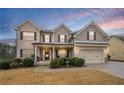 Inviting two-story home featuring a brick and siding exterior, front porch, and manicured landscaping at 1050 Silver Thorne Dr, Loganville, GA 30052