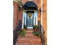 Elegant front entry with a decorative glass door, black awning, potted plants, and brick steps at 1210 Thistle Gate Path, Lawrenceville, GA 30045