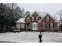 Lovely two-story home in winter with snow-covered lawn and roof, showcasing its curb appeal at 1210 Thistle Gate Path, Lawrenceville, GA 30045