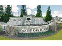 Landscaped entrance sign for Water Oak Estates, surrounded by lush greenery and seasonal flowers at 1818 Lacebark Elm Way, Lawrenceville, GA 30045