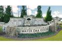 Stone entrance sign for Water Oak Estates, surrounded by manicured landscaping and seasonal flowers at 1891 Lacebark Elm Way, Lawrenceville, GA 30045