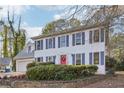 Charming two-story home with a red front door and blue shutters surrounded by mature trees on a sunny day at 615 Heartwood Se Way, Conyers, GA 30094