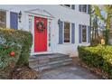 Close-up of the inviting red front door framed by classic sidelights, blue shutters, and decorative landscaping at 615 Heartwood Se Way, Conyers, GA 30094