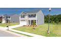 Beautiful gray two-story home with a manicured lawn, complemented by a young tree in the front yard at 195 Amberjack Trl, Covington, GA 30016