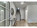 Inviting entryway featuring wood floors, staircase, and a view into a light-filled bathroom at 1236 Ainsworth Aly # 37, Sugar Hill, GA 30518