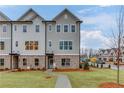 Beautiful three-story townhome with a well-manicured front lawn and a paved walkway at 1236 Ainsworth Aly # 37, Sugar Hill, GA 30518