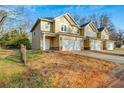 Side view of the tan townhome featuring a two-car garage at 6880 Robinson St, Lithonia, GA 30058