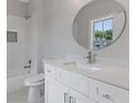 Bright bathroom with a round mirror, white vanity, and a tiled shower/tub combo, offering a clean and modern feel at 230 Trecastle Sq # 25, Canton, GA 30114