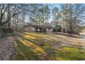 Exterior shot of home with grass lawn surrounded by tall trees at 1350 Piedmont Rd, Marietta, GA 30066