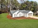 Exterior view of a well-maintained home with a two-car garage surrounded by lush landscaping at 1666 Hearthstone Way, Jonesboro, GA 30236