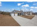 Exterior view of a blue home with stone accents, a long driveway and manicured lawn at 7438 Jennadee Dr, Fairburn, GA 30213